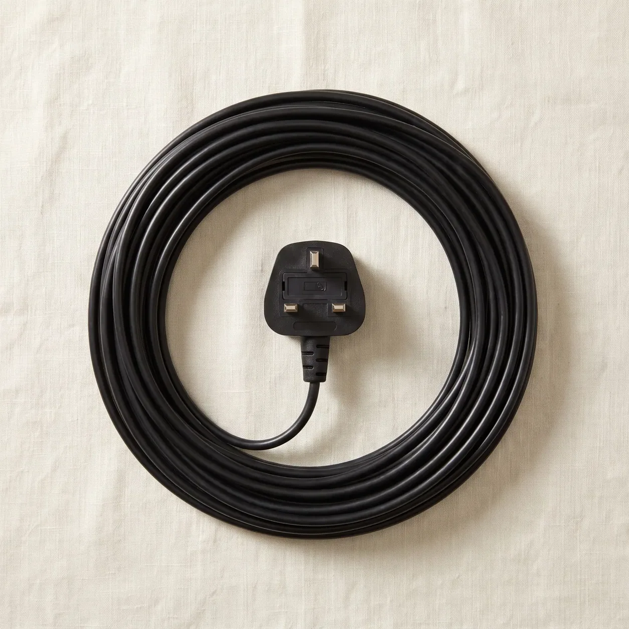 A neatly coiled vacuum cleaner cable with a UK three-pin plug